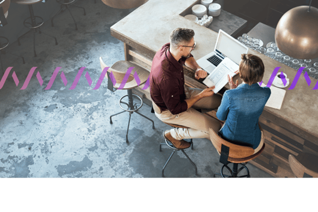Image of two workers sitting on stools at a counter with a laptop, reviewing paperwork